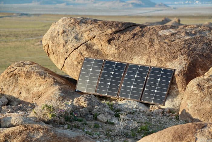 80 watt solar panel charger leaned against a rock to charge a phone on a hike.