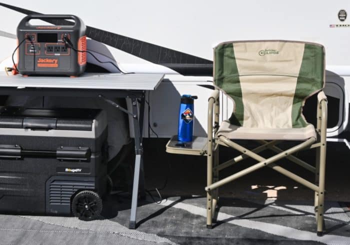 Jackery 1500 portable power station next to an RV and a camping chair