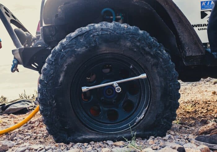 truck with a flat tire using an RV tire inflator portable air compressor to inflate it