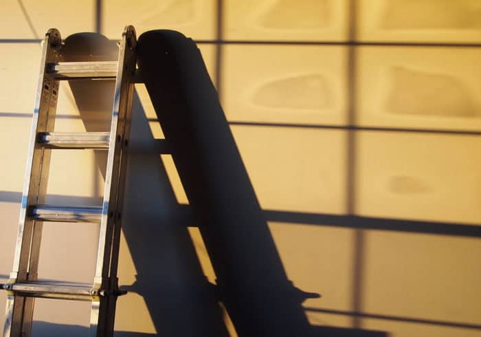 collapsible and telescoping ladder leaning against a wall