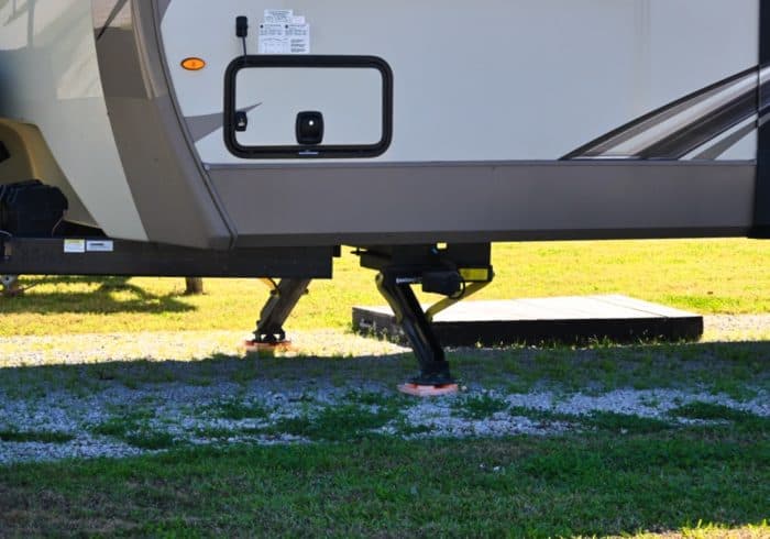 stabilizer jacks on a travel trailer in an rv park with stabilizer blocks underneath