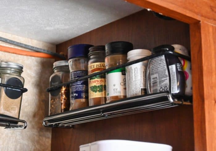 wall mounted spice rack inside a small rv kitchen cabinet for organizing spices