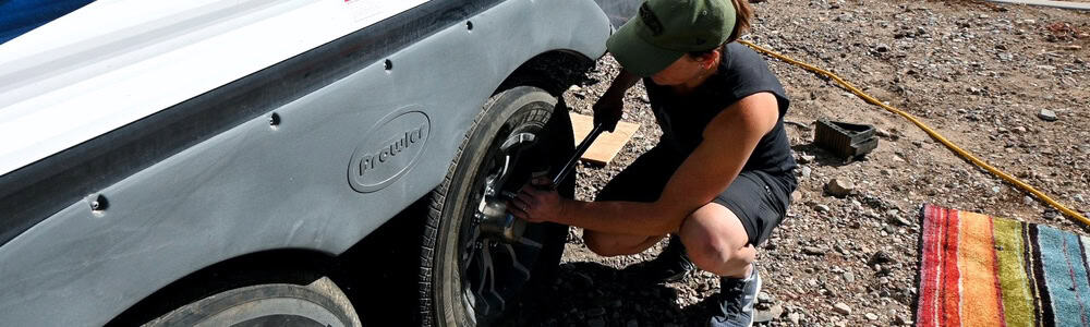 girl tightening lug nuts of a travel trailer tire after changing it using a jack instead of rv stabilizer jacks