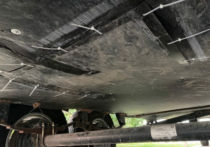 underneath a covered travel trailer RV that was opened to installed RV tank heat pads