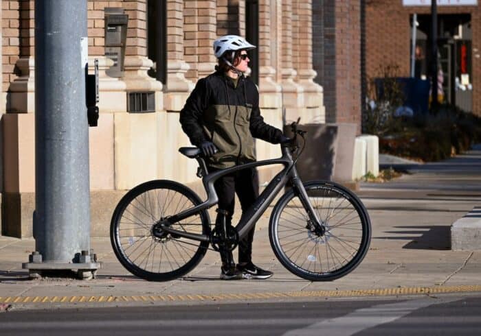 woman waiting to cross a city street with urtopia carbon one smart ebike