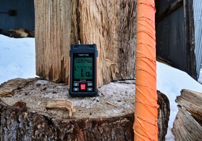 toptes moisture meter being used outside to test firewood for heating a home during winter