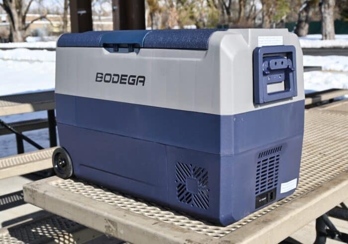 bodega 53 quart 12 volt refrigeratoer sitting on a picnic table in a park