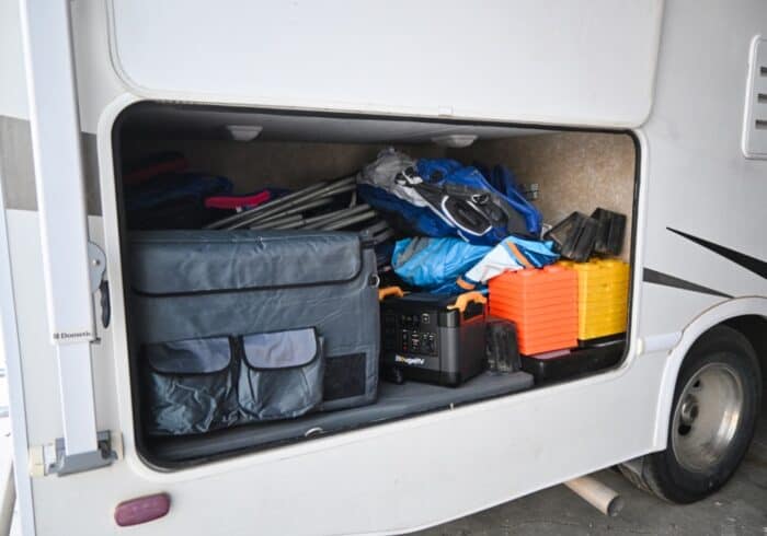 Bodega portable fridge with insulated cover inside an RV storage compartment being powered by a portable power station