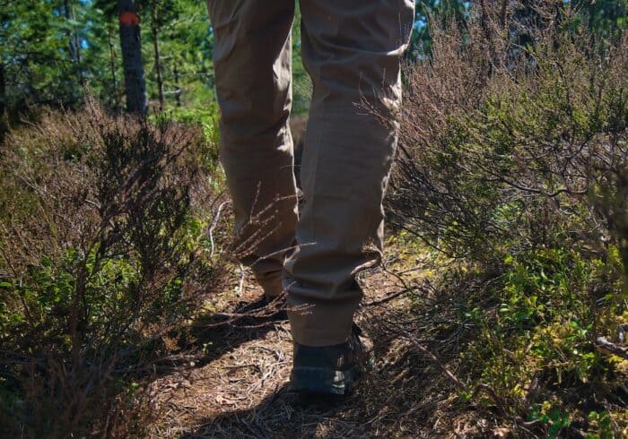Kühl free radikl men's hiking pants being worn on a narrow trail with lots of brush