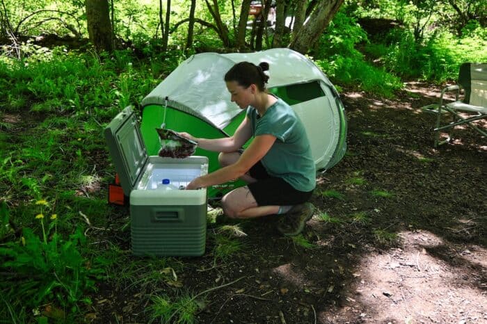 woman getting food from the aaobosi portable fridge while tent and rv camping