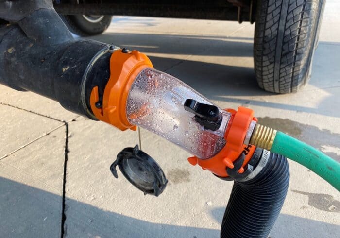 Camco Rhino Blaster Pro tank rinser attached to an RV sewer outlet for back flushing a clogged black tank.